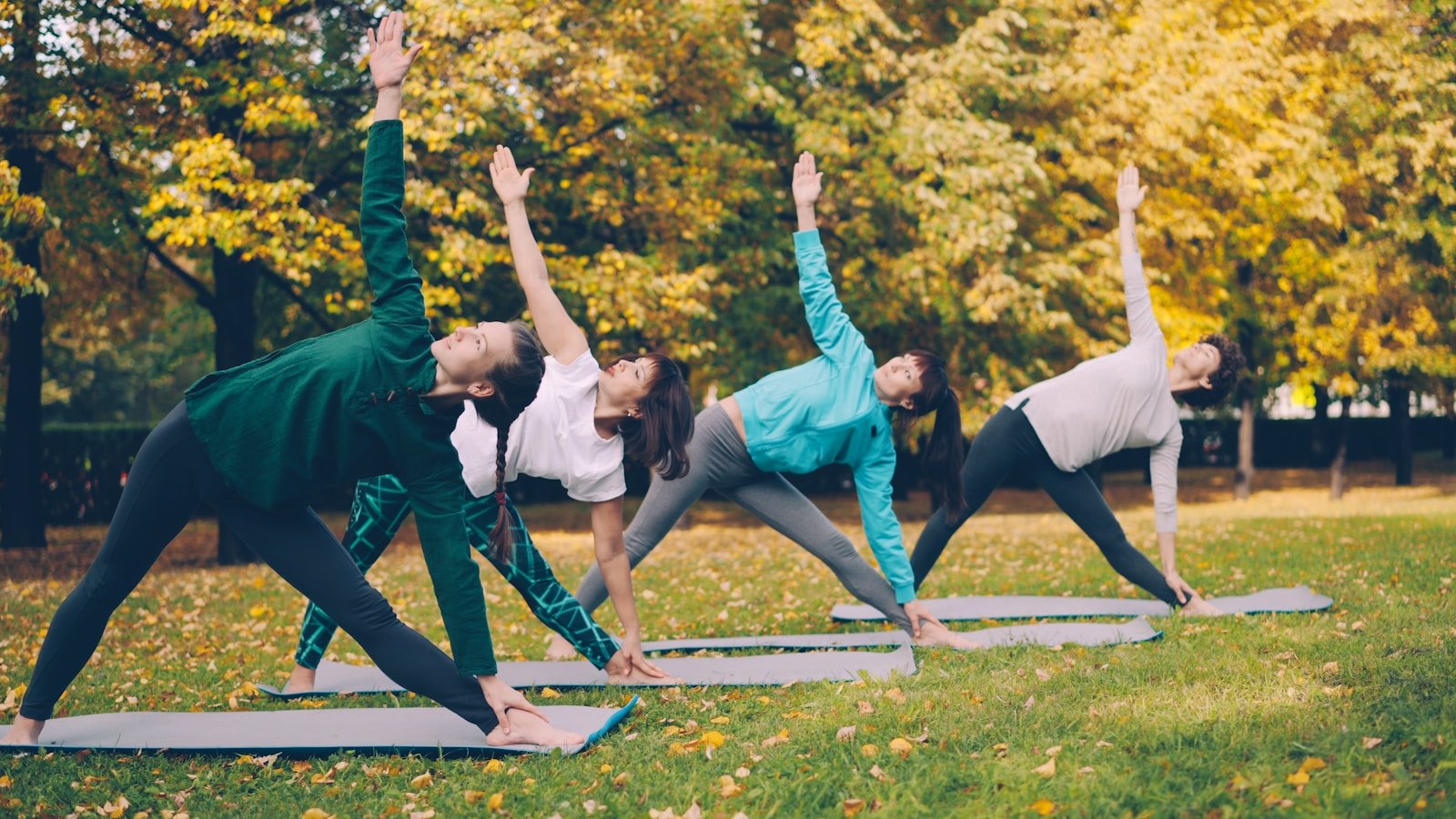 Four people practicing yoga in a park.