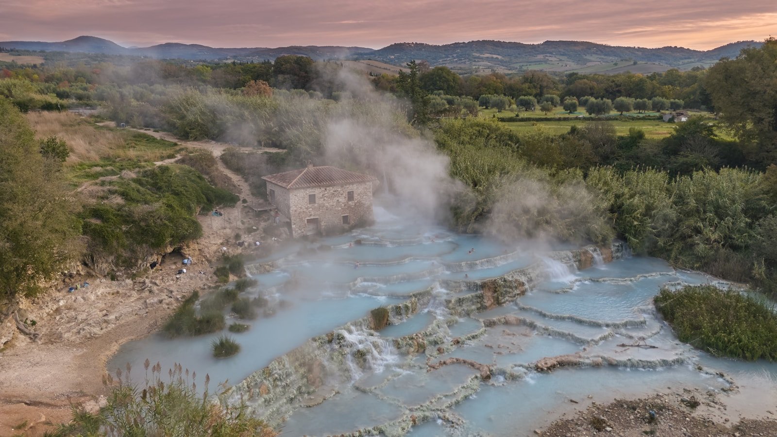 Steaming blue thermal springs with a building in background