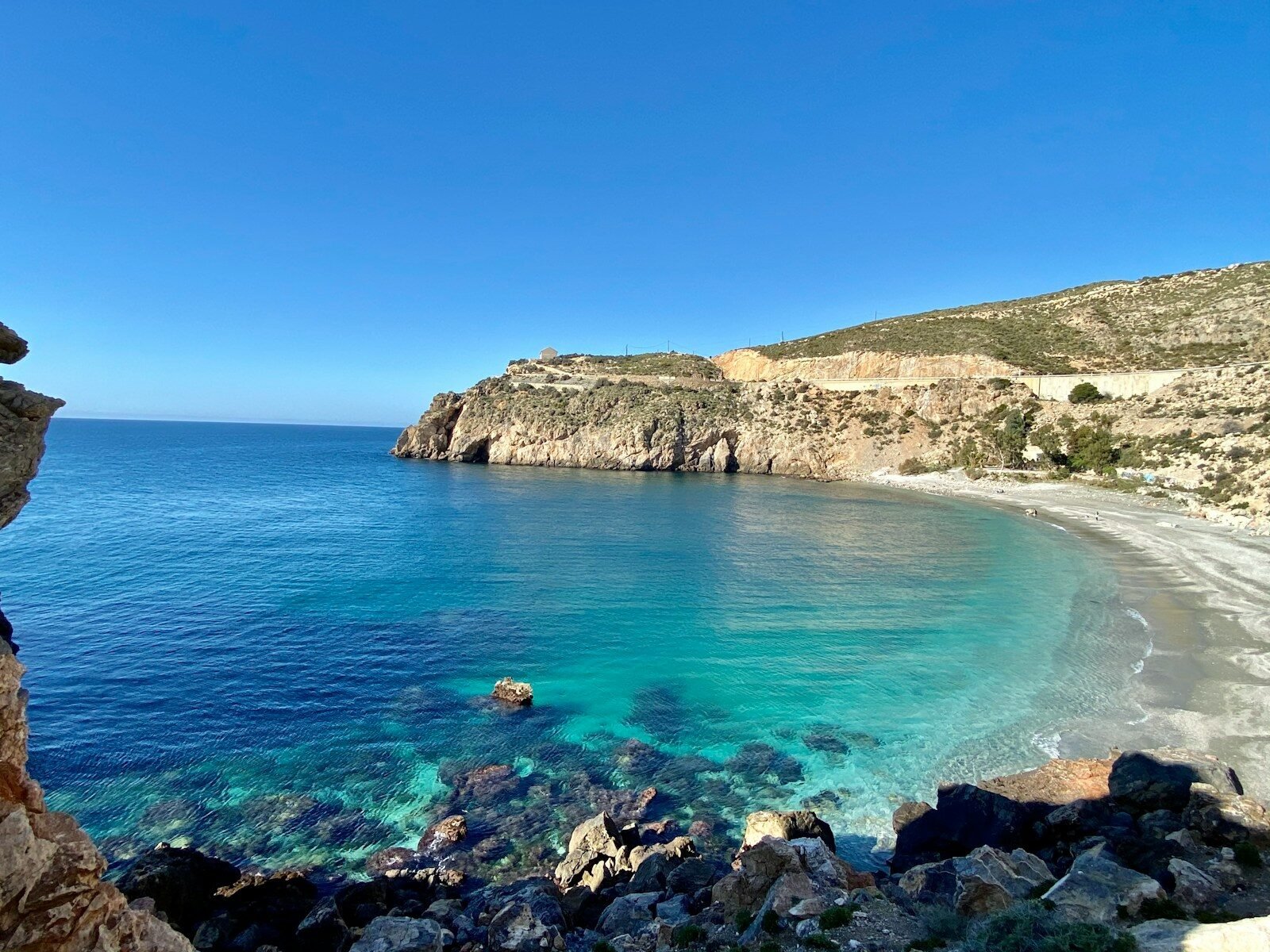 brown rocky mountain beside blue sea under blue sky during daytime