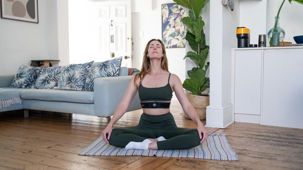 a woman sitting on a yoga mat in a living room